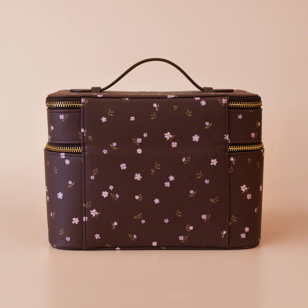 Floral-patterned makeup bag with gold zippers on a beige background