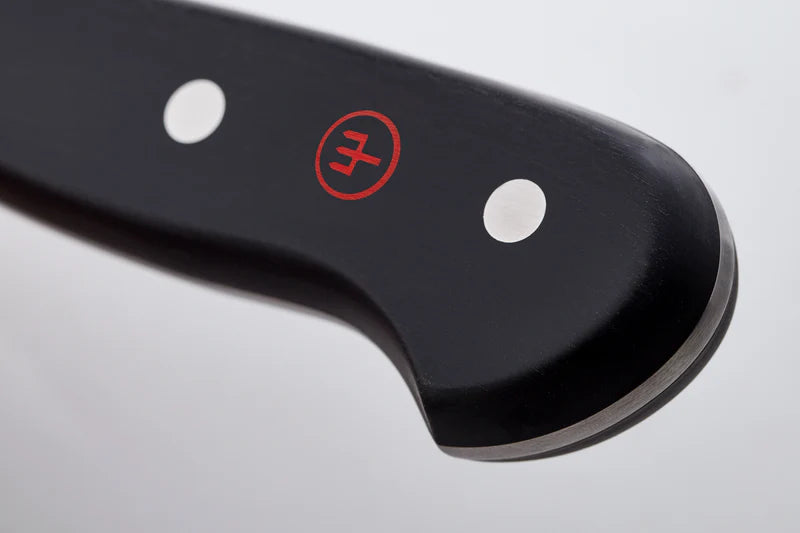 Close-up of a knife blade with a brand logo on a light gray background