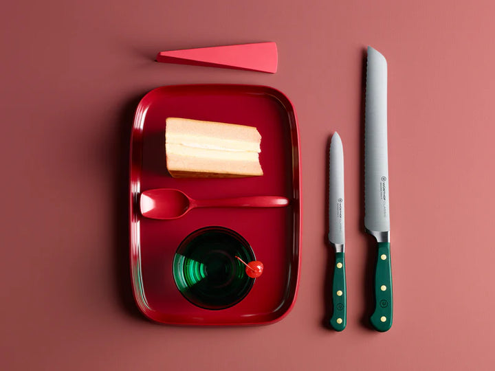Red tray with sliced bread, two knives, on a red background