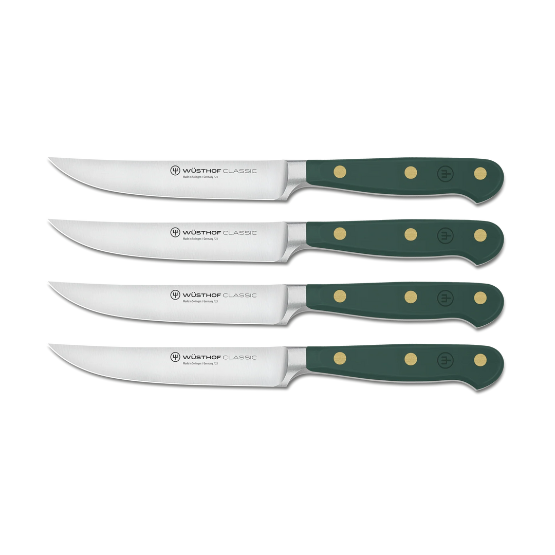 Set of four Wusthof Classic steak knives with green handles on a white background