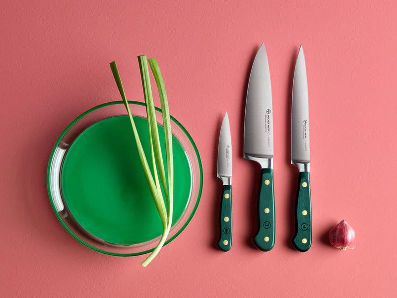 Set of knives with green handles on a pink background