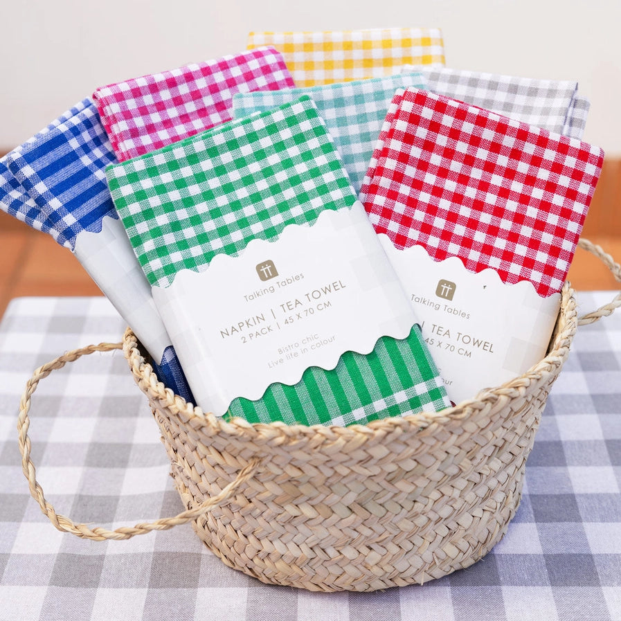 Wicker basket with checkered tea towels on a checkered tablecloth