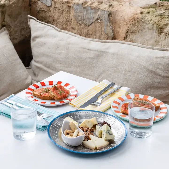 Table setting with plates of food, glasses of water, and cutlery on a stone wall background.