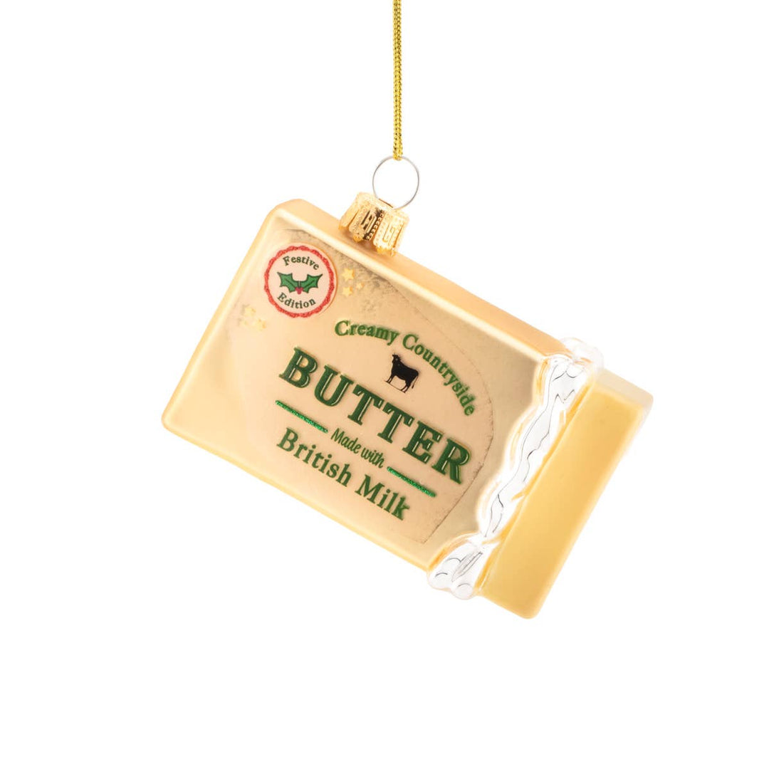 A butter-shaped Christmas ornament styled like a cream-colored butter package with green &