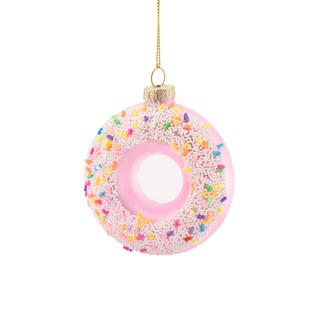 A pink donut-shaped Christmas ornament decorated with white sprinkles and a gold hanging chain, shown against a plain white background.
