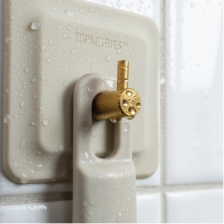 Sand coloured silicone reusable hook stuck to white shower tile