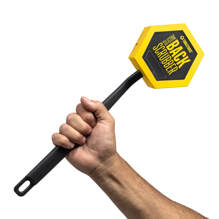 Charcoal coloured silicone back scrubber in packaging, held in front of a white background