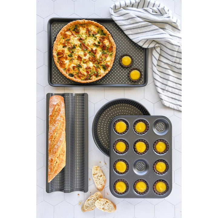 Set of baking trays with various baked goods on a white tiled surface