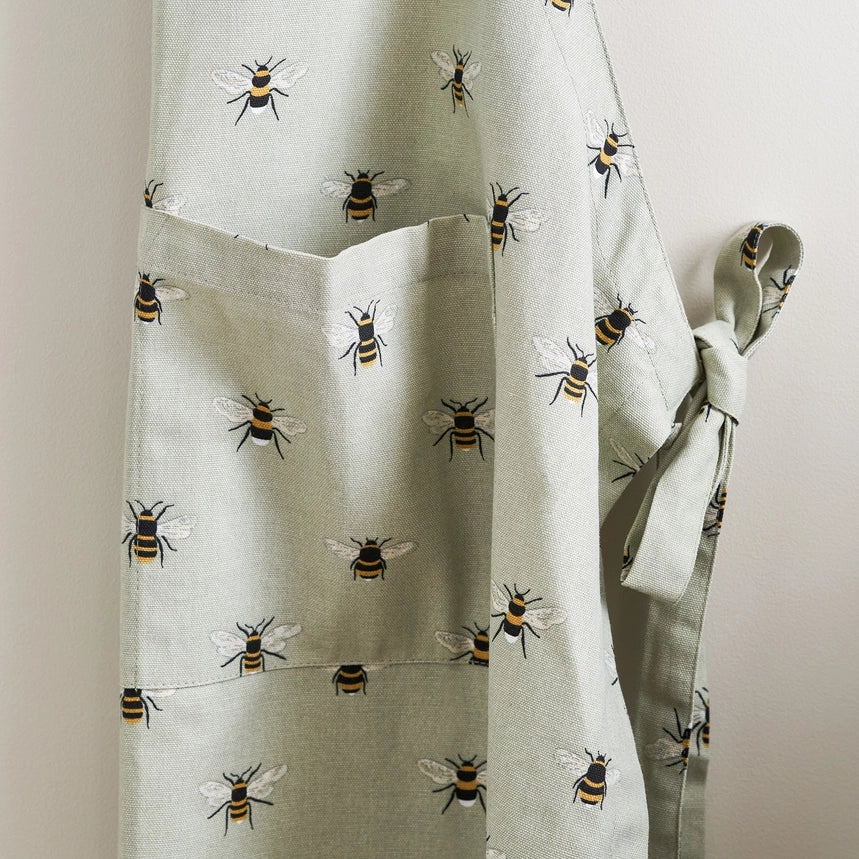 Fabric apron with small bee pattern hanging in front of a white wall