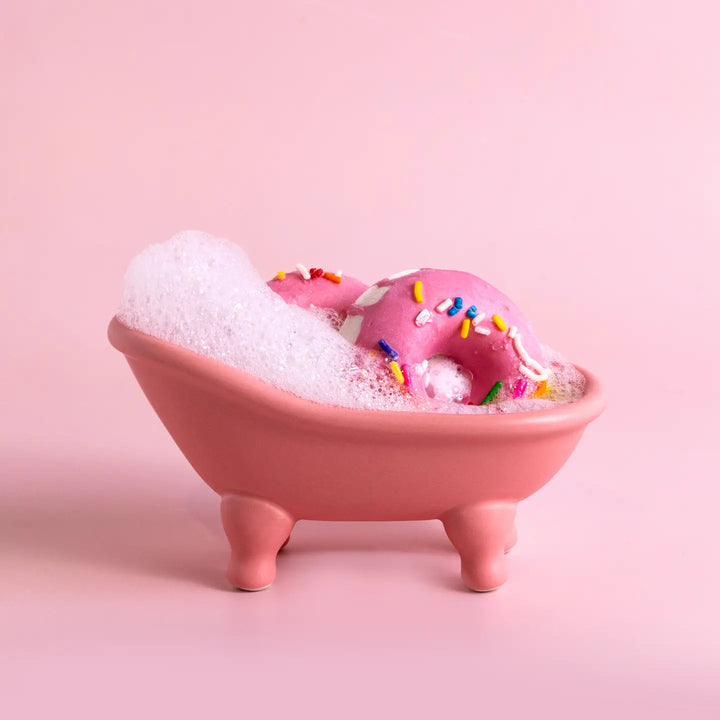 Pink bathtub with a donut and bubbles on a pink background
