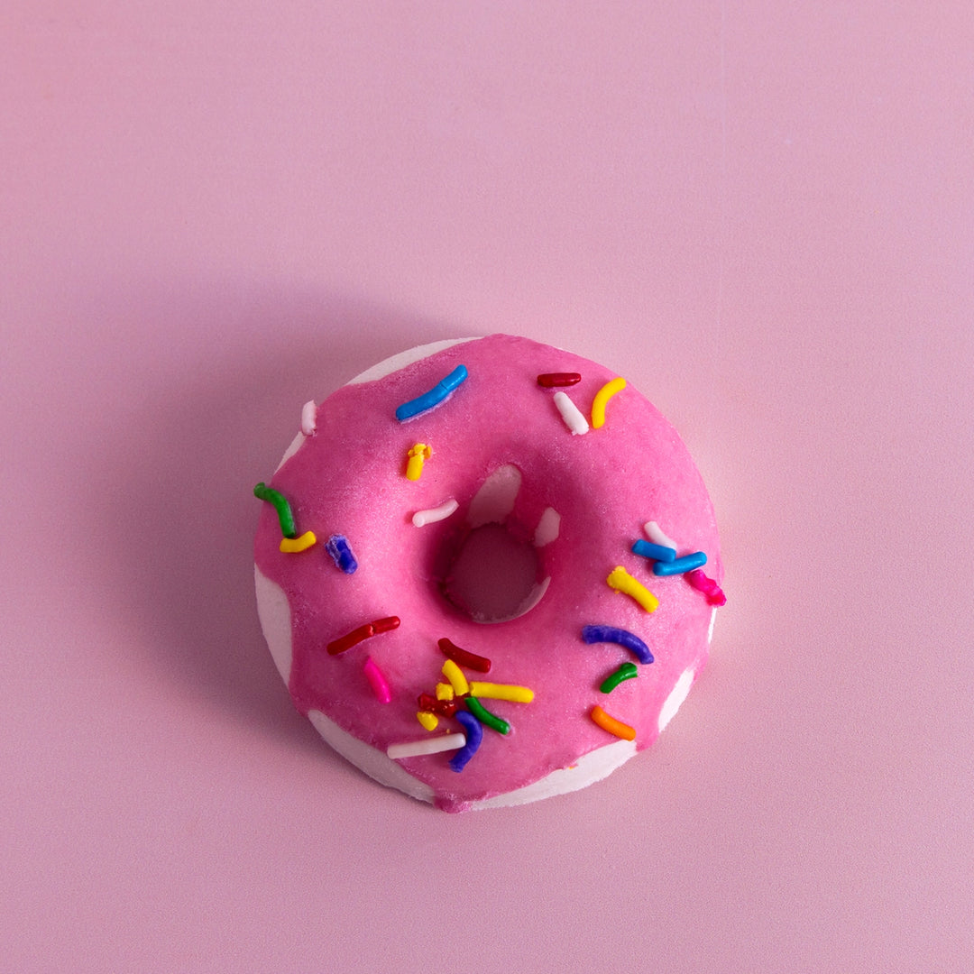 Pink donut with colorful sprinkles on a pink background
