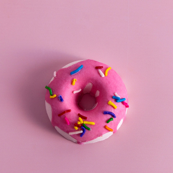 Pink donut with colorful sprinkles on a pink background