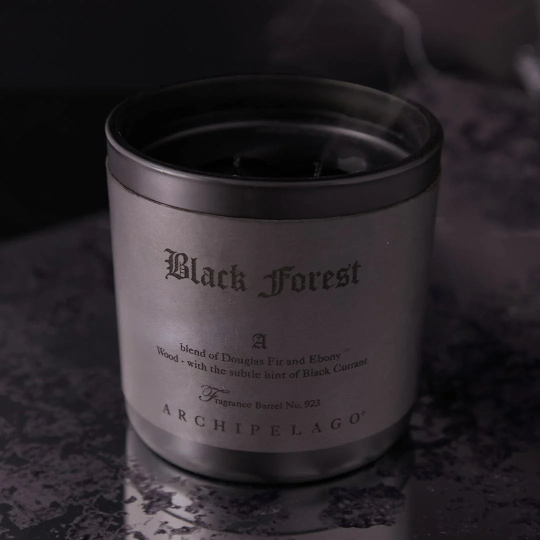 Candle labeled 'Black Forest' by Archipelago on a dark background