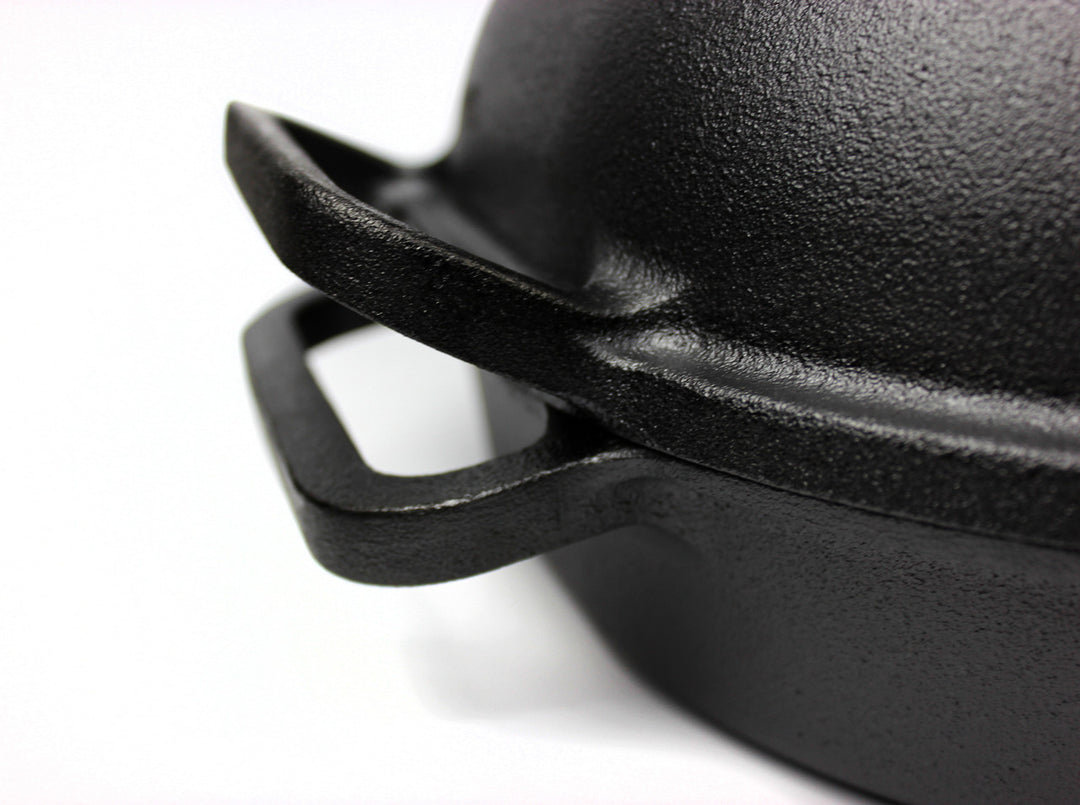 Close-up of a black cast iron pot lid on a white background