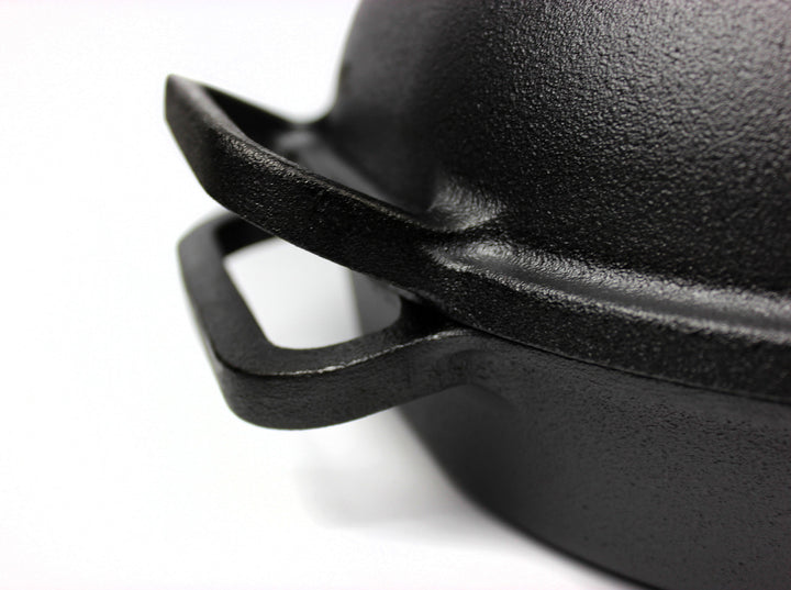 Close-up of a black cast iron pot lid on a white background
