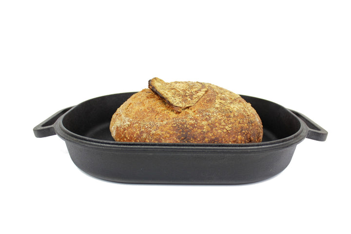 Loaf of bread in a black cast iron bread pan on a white background