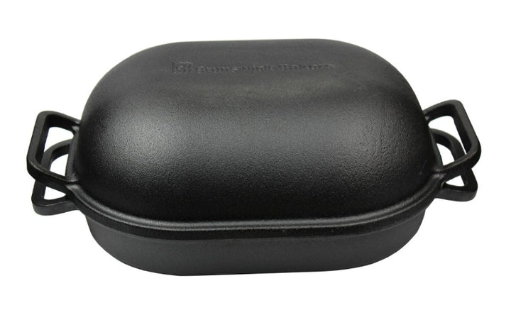 Black cast iron roaster with handles on a white background