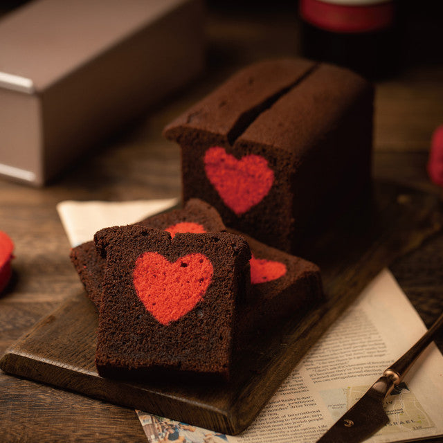 Chocolate bread with red heart designs on a wooden board.