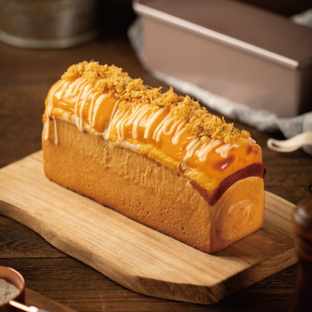 Loaf of bread with a topping on a wooden cutting board