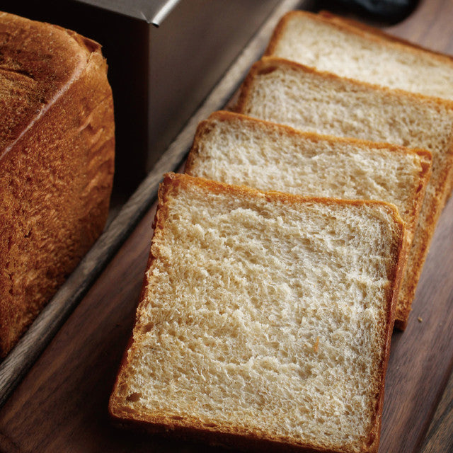 Loaf of bread with sliced pieces on a wooden surface