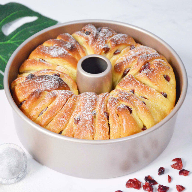 Braided bread in a round baking pan on a white background