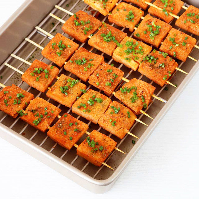 Skewers of salmon with green herbs on a metal tray