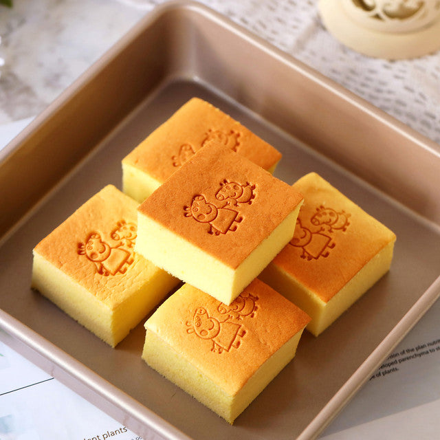 Square yellow cakes with a design on top of a brown tray.