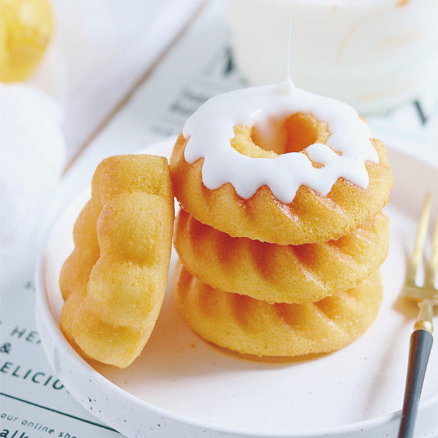 Stack of small donuts with white icing on a plate with a gold fork.
