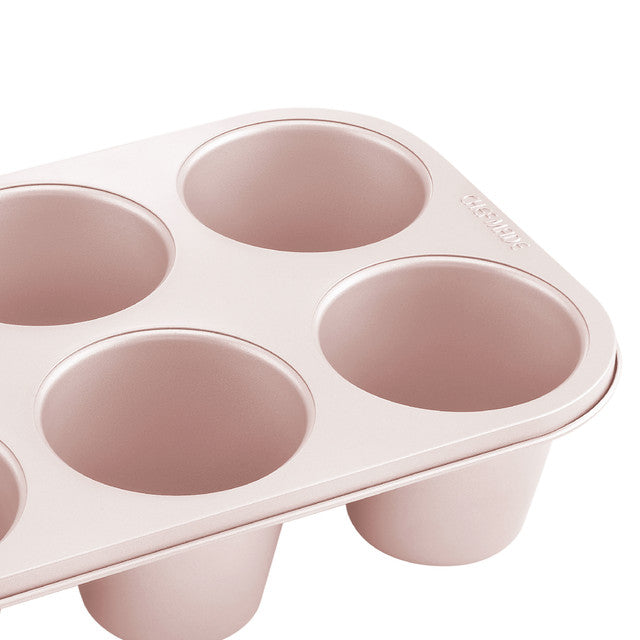 Pink muffin tin with six compartments on a white background