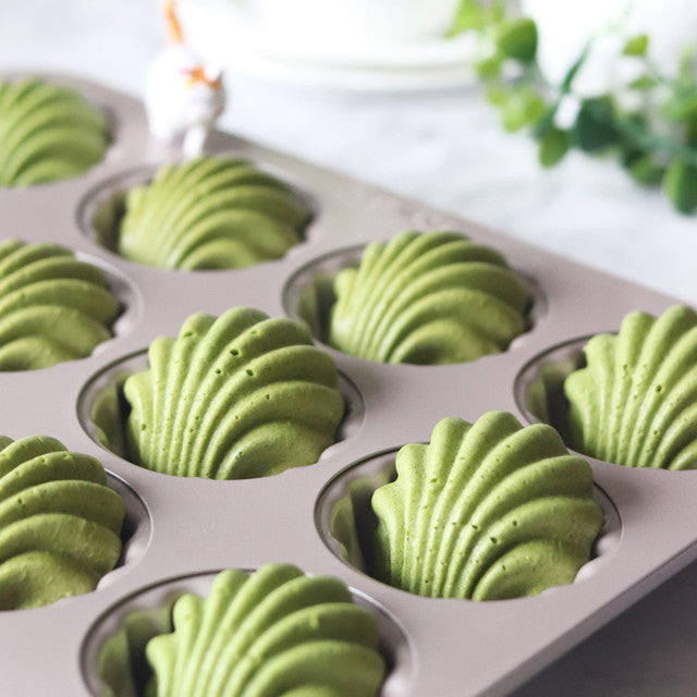 Green baked goods in a muffin tin with a blurred background
