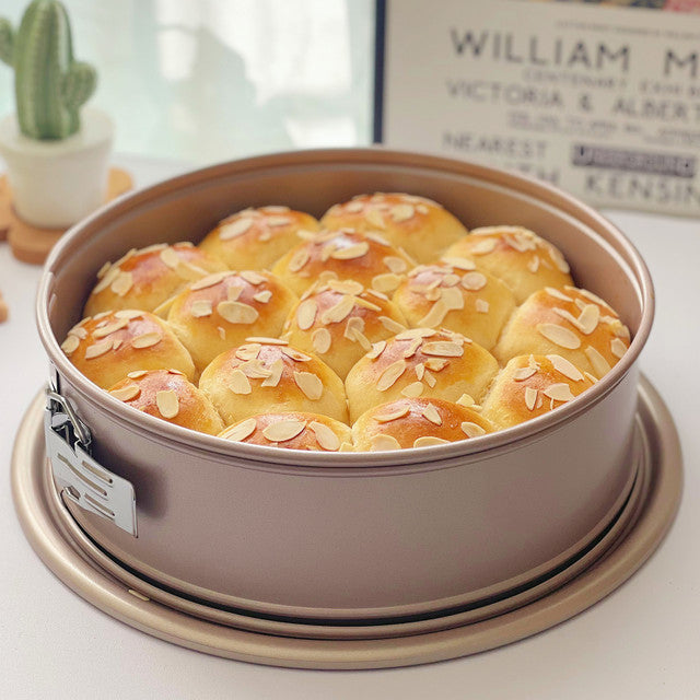 Round baking pan with golden brown baked goods on a light surface.
