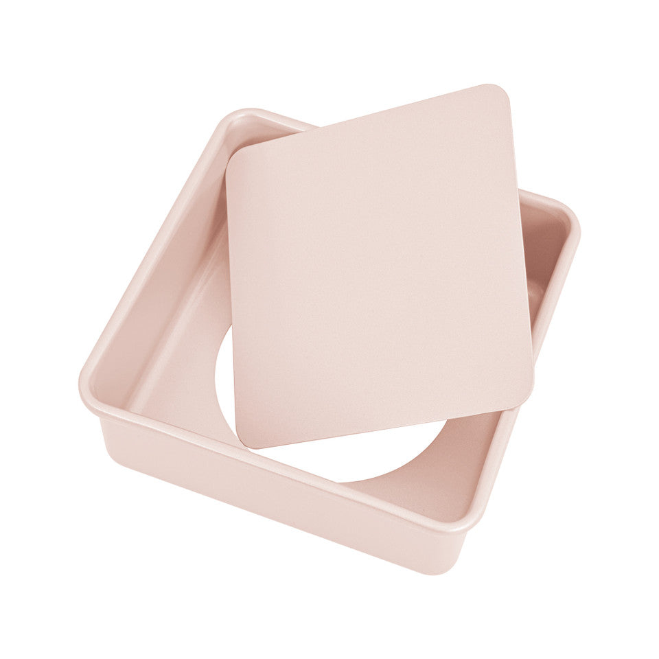 Pink square baking tin with loose base on a white background