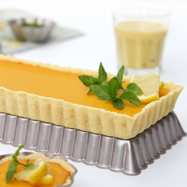 Yellow tart with a leafy garnish on a white surface