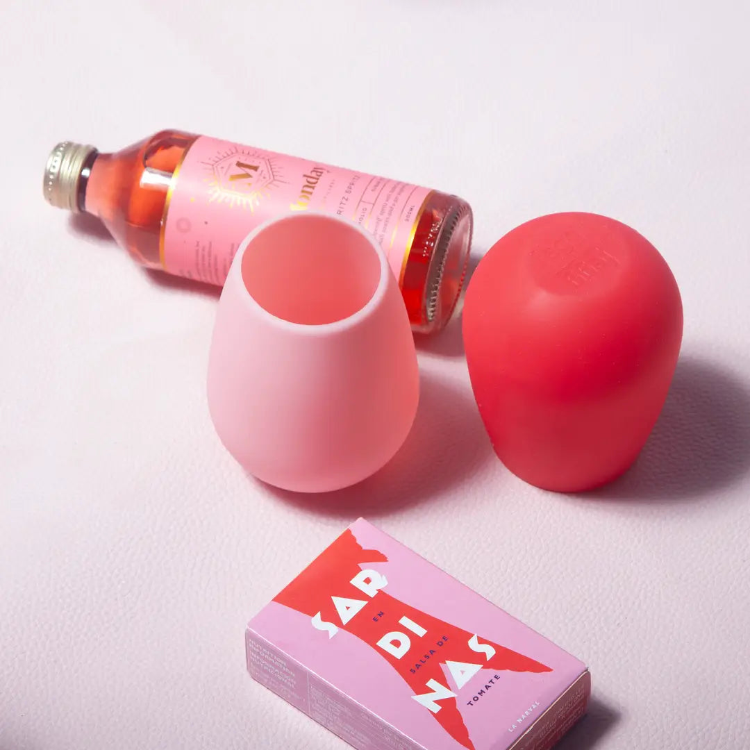 Pink and red silicone items with a bottle on a light pink background