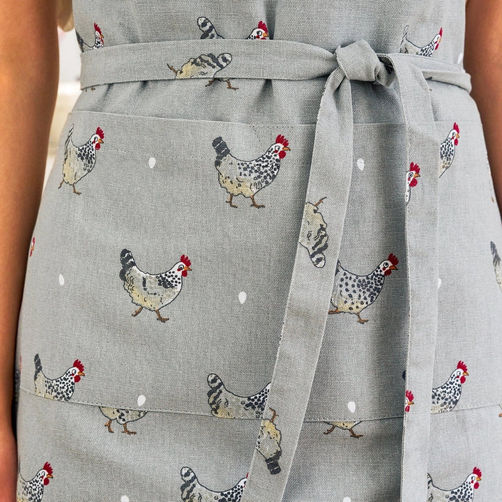 Gray fabric apron with a repeating chicken pattern, tied at the waist