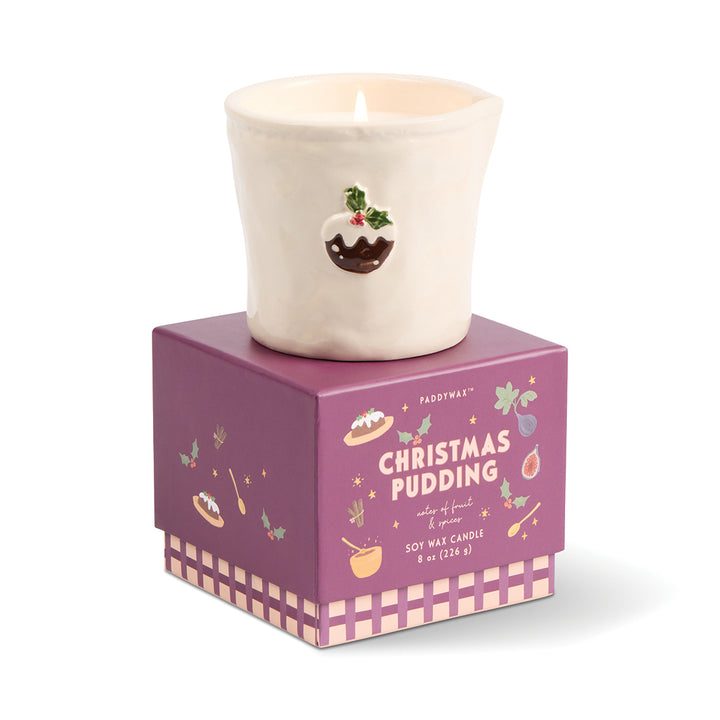Candle in a Christmas pudding design container on a white background
