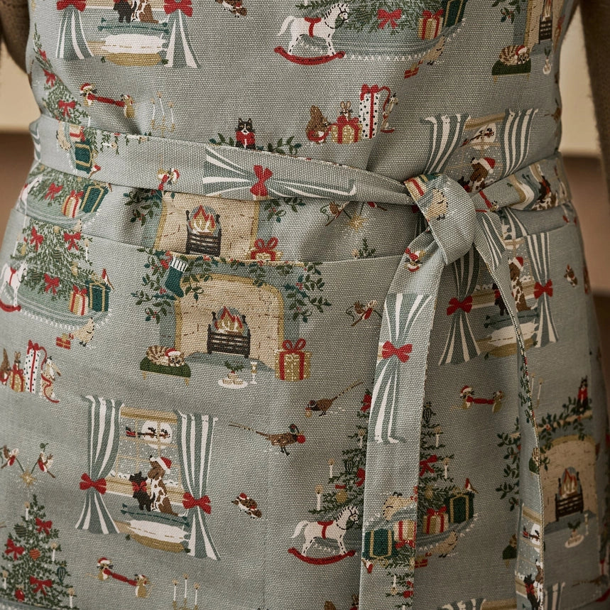 Apron with a detailed holiday fireplace illustration pattern tied around the waist