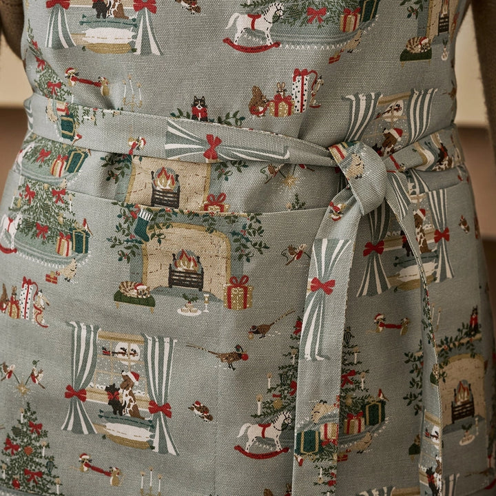 Apron with a detailed holiday fireplace illustration pattern tied around the waist
