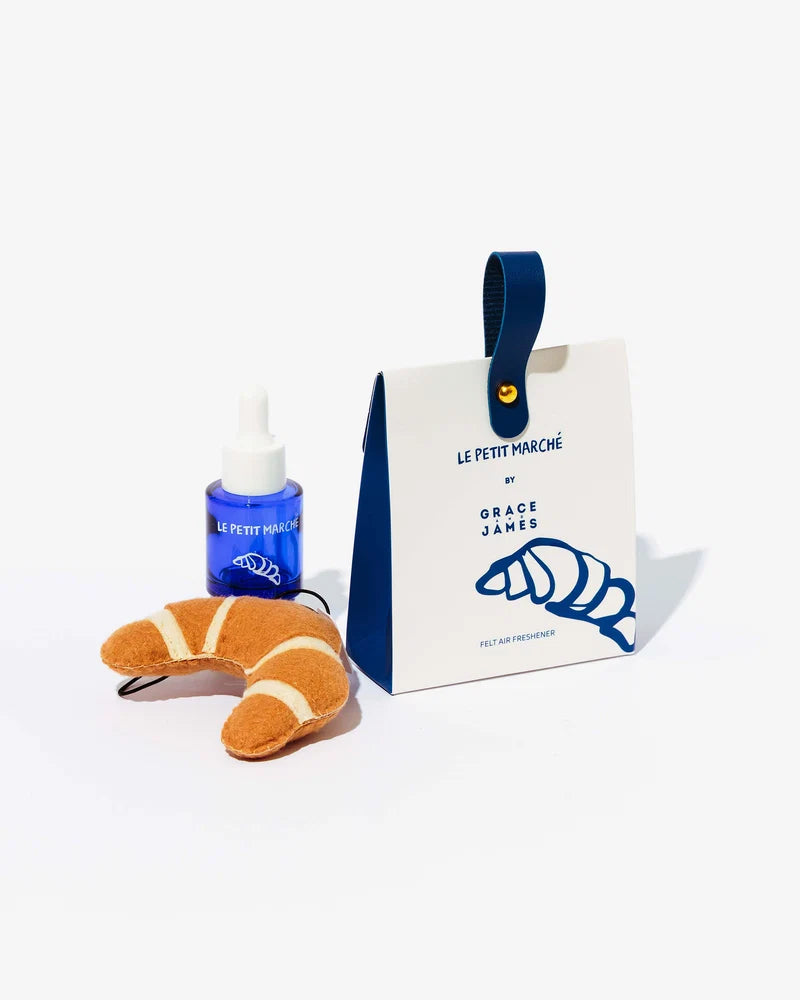 A photo of Grace & James croissant air freshener with a blue bottle of fragrance
