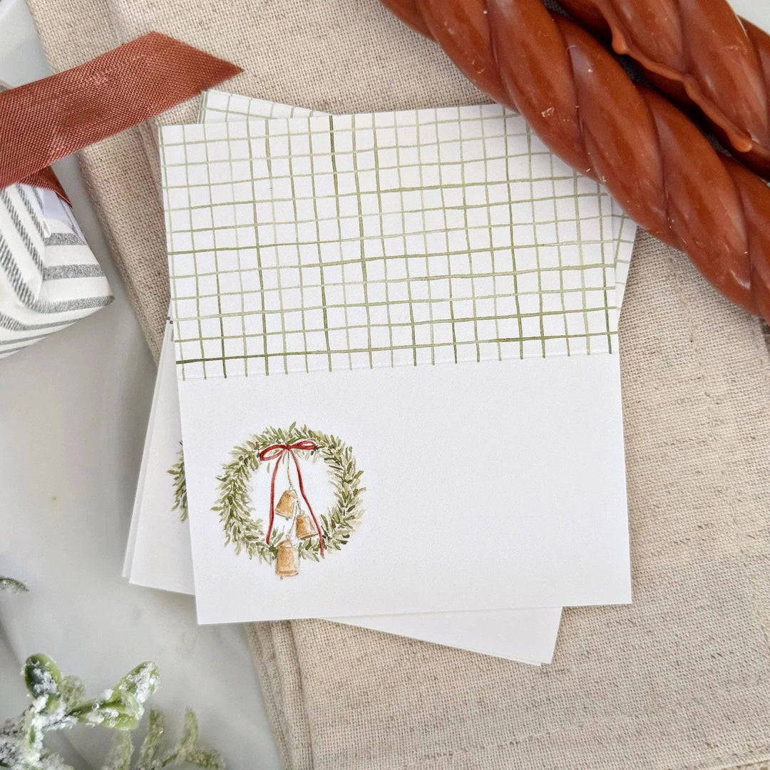 Stack of Christmas place cards with a Christmas wreath design on a textured surface