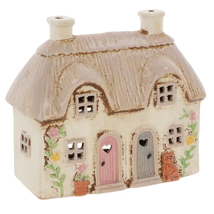 A ceramic house tealight holder with 2 doors, flowers and a cat on a white background 