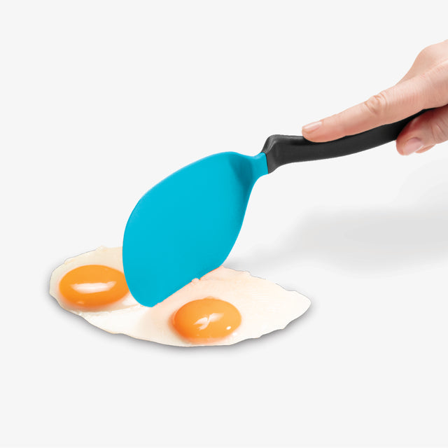 Blue spatula lifting a fried egg with a white background