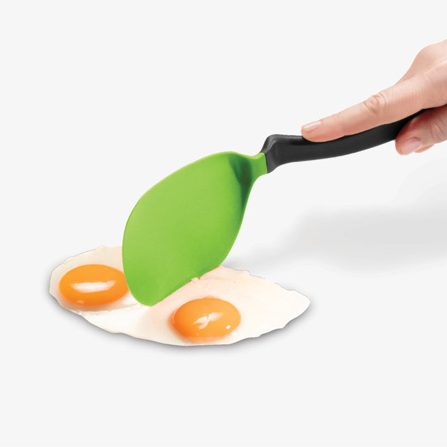 Green spatula lifting a fried egg with a white background