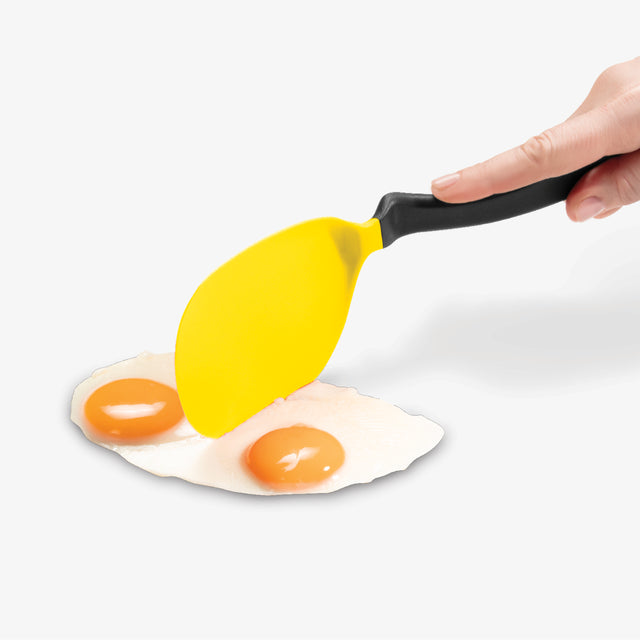 Yellow spatula lifting a fried egg with a white background