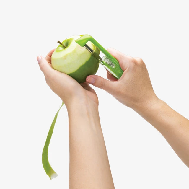 Person using a green apple peeler on a white background