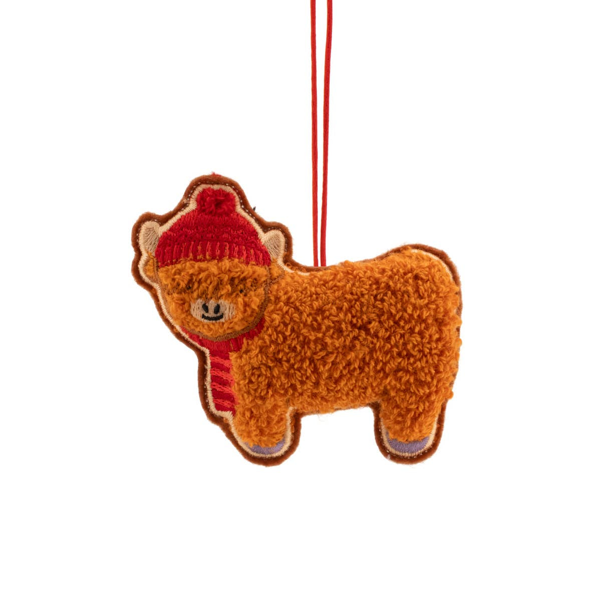 A plush highland cow-shaped Christmas ornament in warm brown, wearing a red knit hat and matching red striped scarf, hanging by a red string against a plain white background.