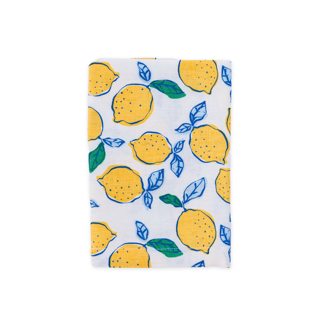A white linen napkin featuring a vibrant yellow lemon and blue leaf pattern, shown flat against a solid white background.