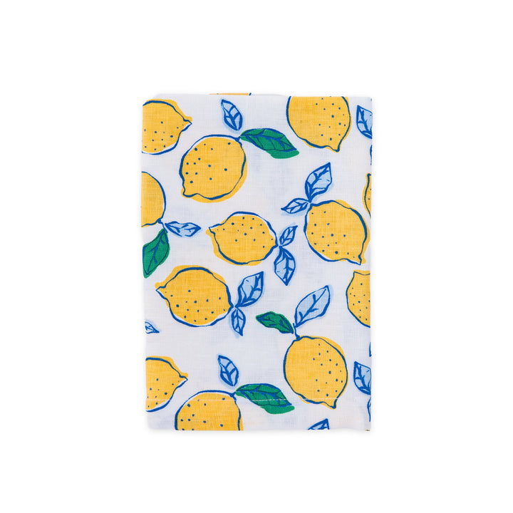 A white linen napkin featuring a vibrant yellow lemon and blue leaf pattern, shown flat against a solid white background.