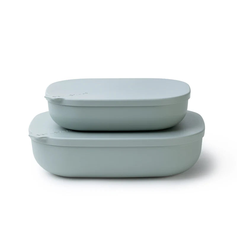 Two oval plastic containers with matching lids in a muted sage green color, stacked on a clean white background.