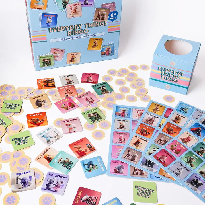 Everyday Things Bingo game set with a blue storage box, a smaller matching box, and many colorful bingo cards and round yellow tokens scattered on a white surface.